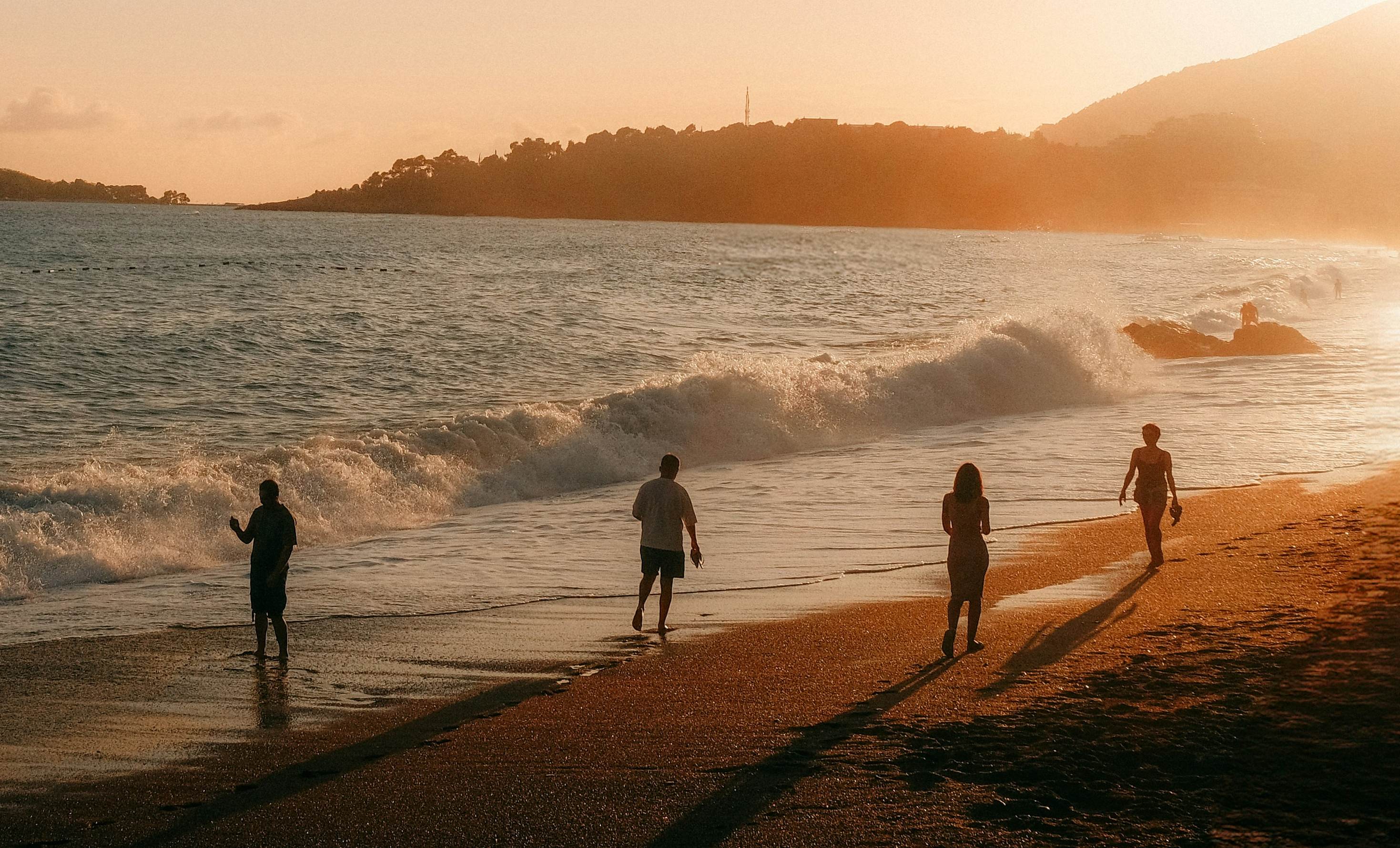 people walking on a beach at sunset